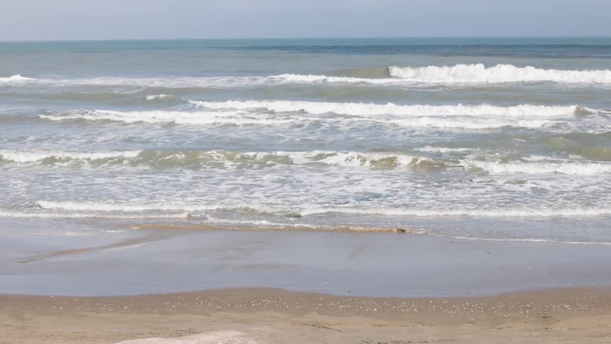 Waves roll into shore and over the beach