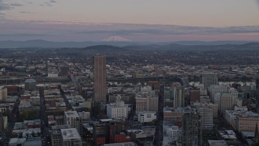 Aerial panoramic of downtown portland oregon at dawn with mt hood jutted into a hazy purple morning sky in the background