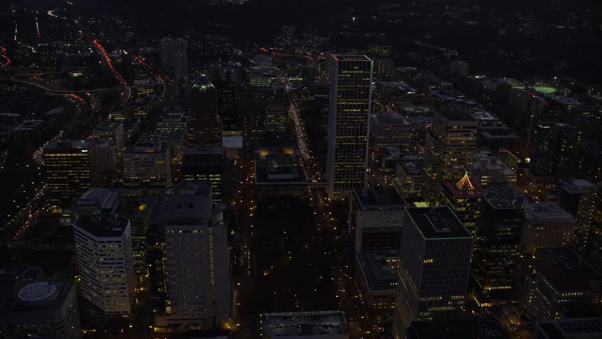Aerial panorama of a metropolis with nighttime skyscrapers by the sea and a purple evening sky