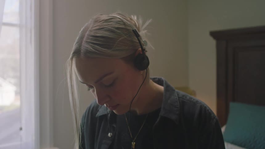 A woman listening to music on an mp player in her bedroom