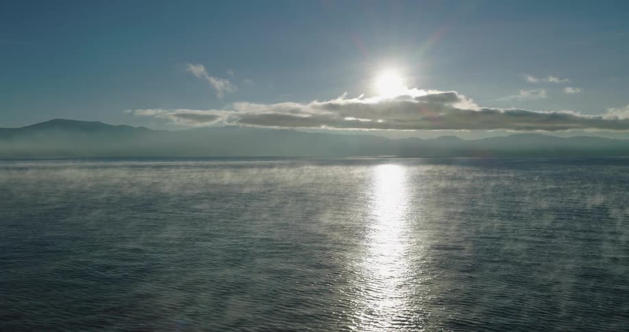 Aerial panorama of the sea with calm waves and the reflection of the sun
