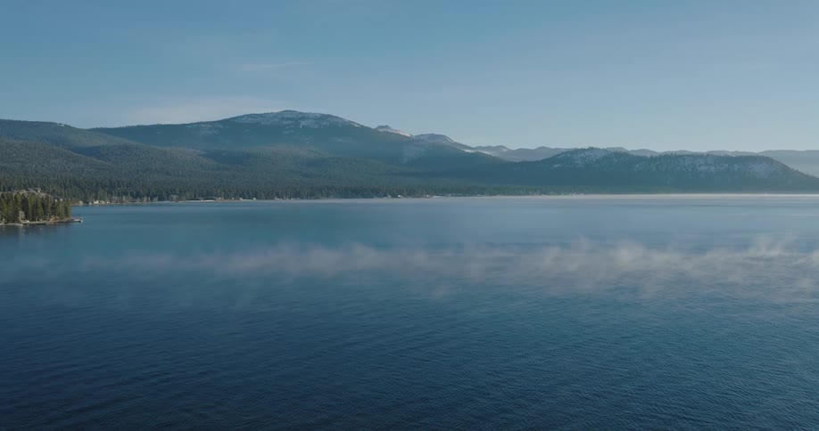 Aerial of sea with coast with forests and mountains during a sunny day
