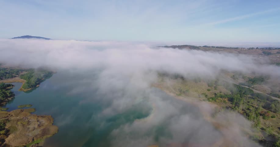 Panorama of a river surrounded by forests covered in mist in daylight