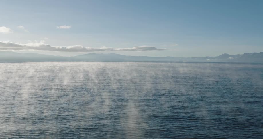 A pan across a large body of water with patches of fog across the surface