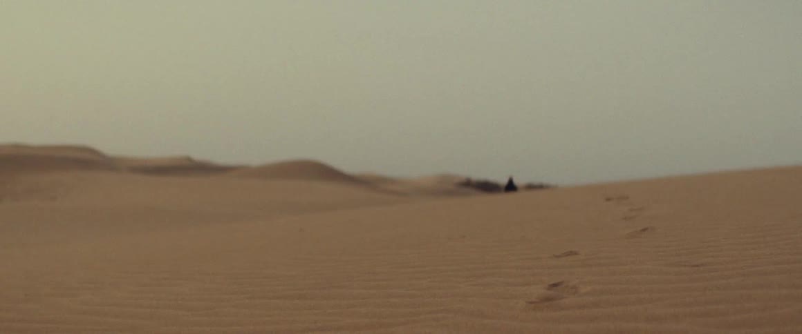 Someone walking through the desert leaving behind footprints in the sand