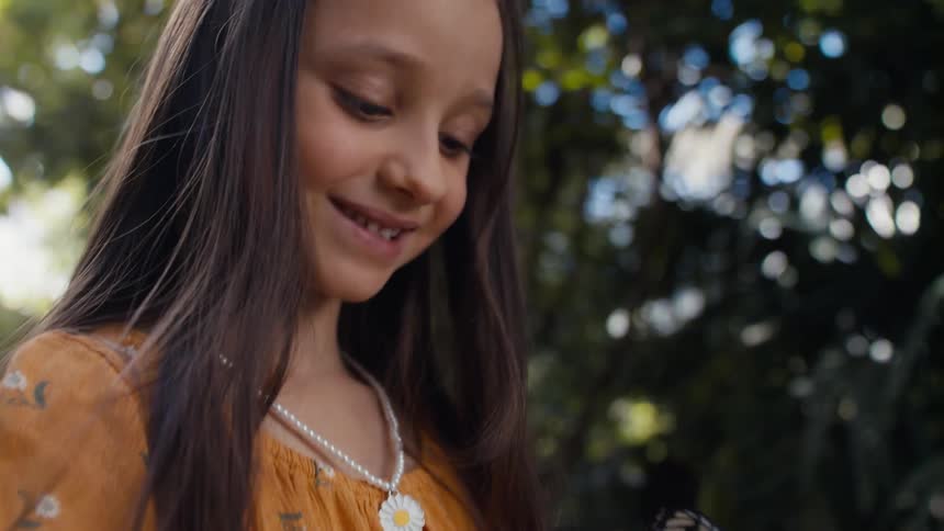 A clip of a young female kid holding a butterfly