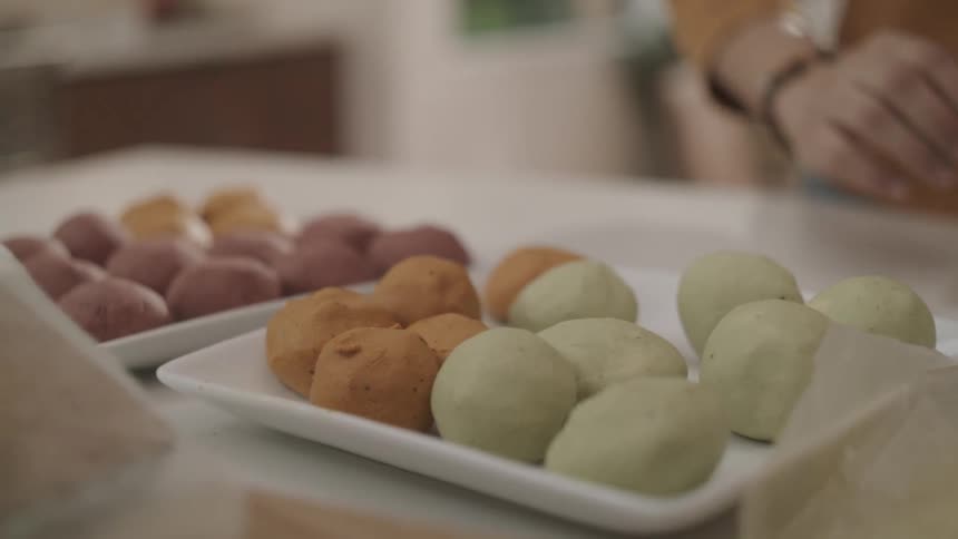 A person rolling balls of colorful dough