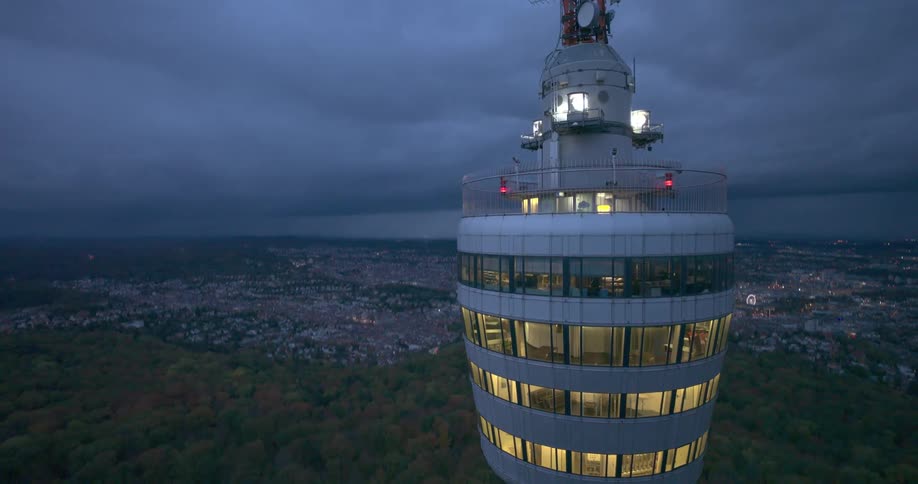 View of an illuminated tower amidst a natural environment next to a city