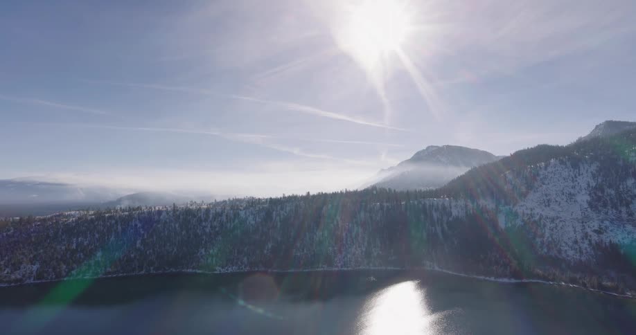 Aerial of forest in snowcovered mountains during a sunny day