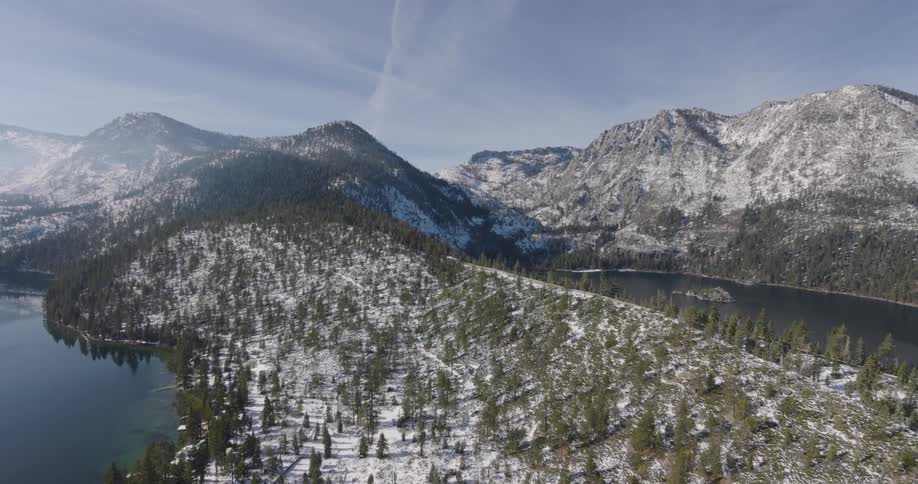 Aerial panorama of a mountain range with coniferous trees and snow amidst lakes