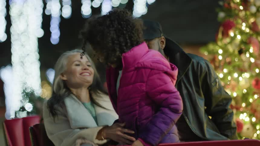Parents and daughter get into a carriage and mother hugs her daughter as she sits on her lap