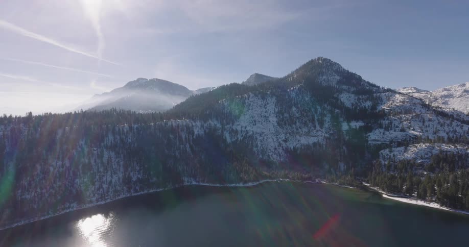 Aerial of a lake with snowcapped mountains during a sunny winter day