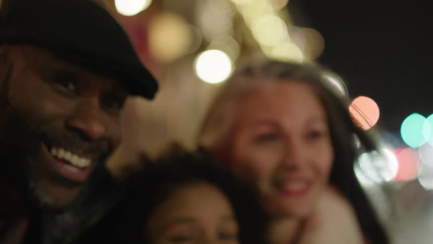 Portrait of a family with parents and a daughter smiling in the midst of a city at night