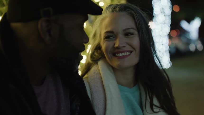 A man and woman talk outside at night