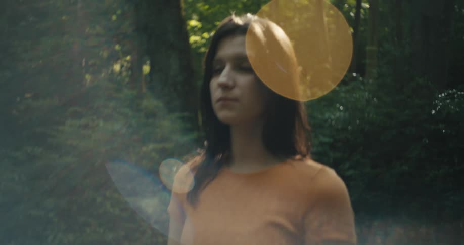 Young woman stands still in the forest at daytime