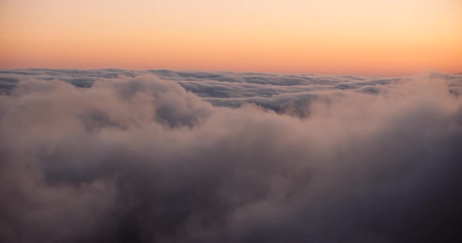 Aerial above clouds against a setting sun