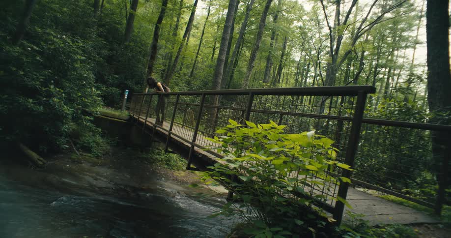 A woman hikes over the stream