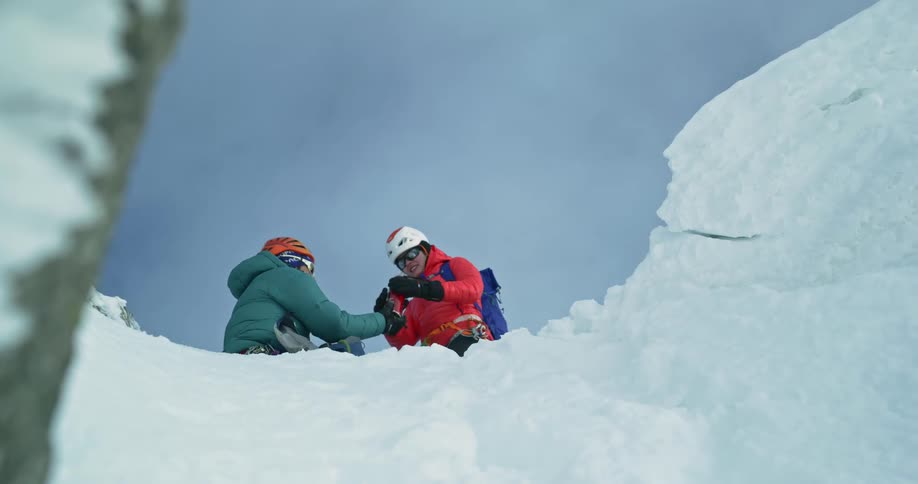 Two mountain climbers open a thermos