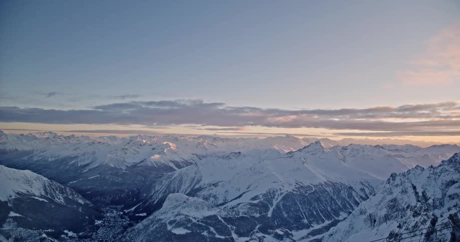 Snow covered mountains stretch across the landscape under a cloudy sky