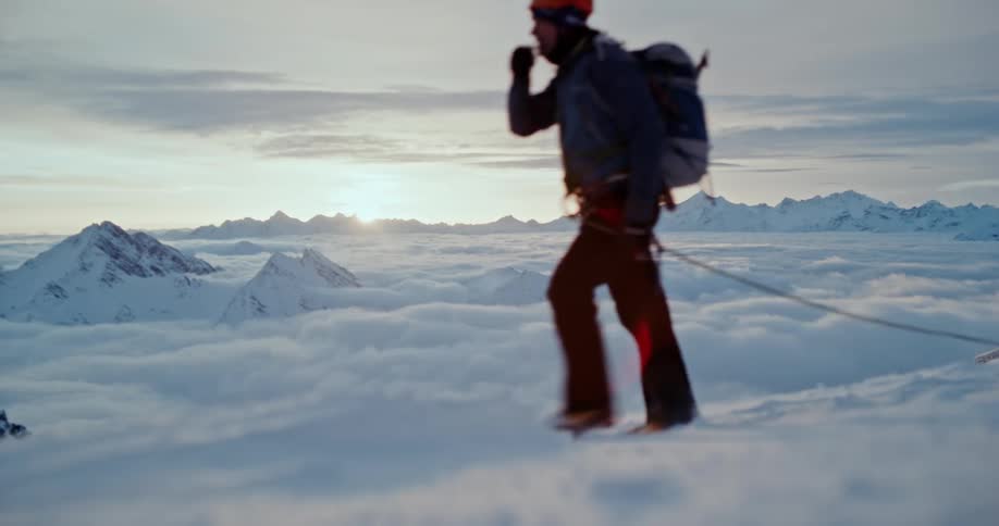 A man walking on a snowy mountain during sunset