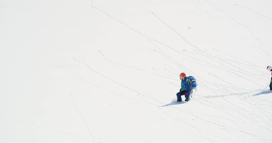 Two people climbing a snowy mountain on a sunny day