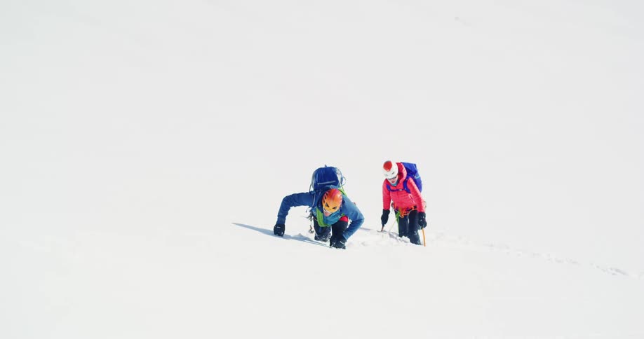 Two mountain climbers struggle through kneedeep snow