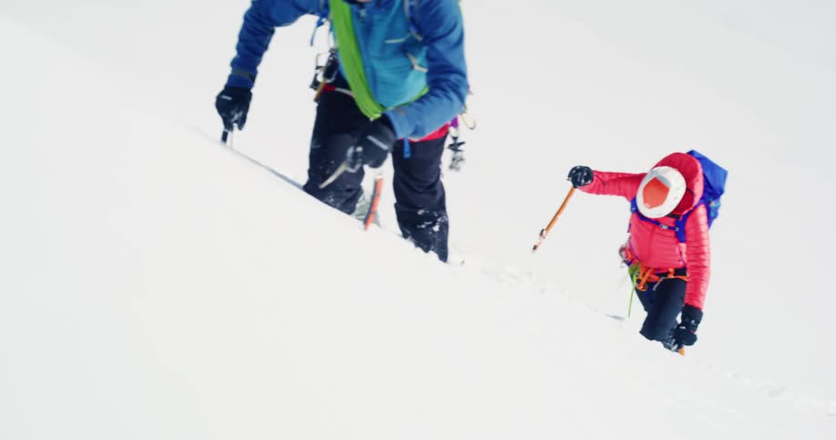 Two people are climbing up the snow filled mountain