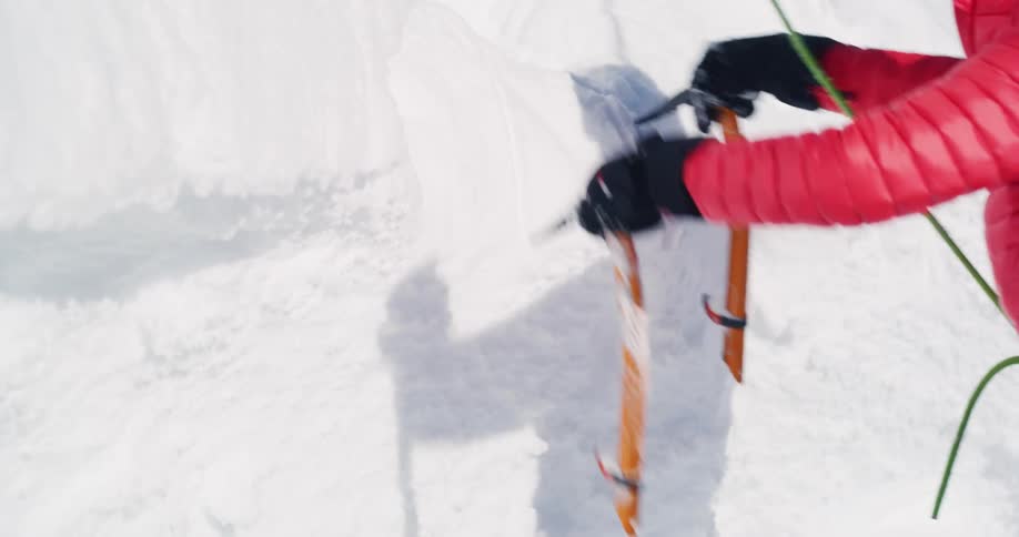 Mountaineer prepares to climb a snow wall in the mountains