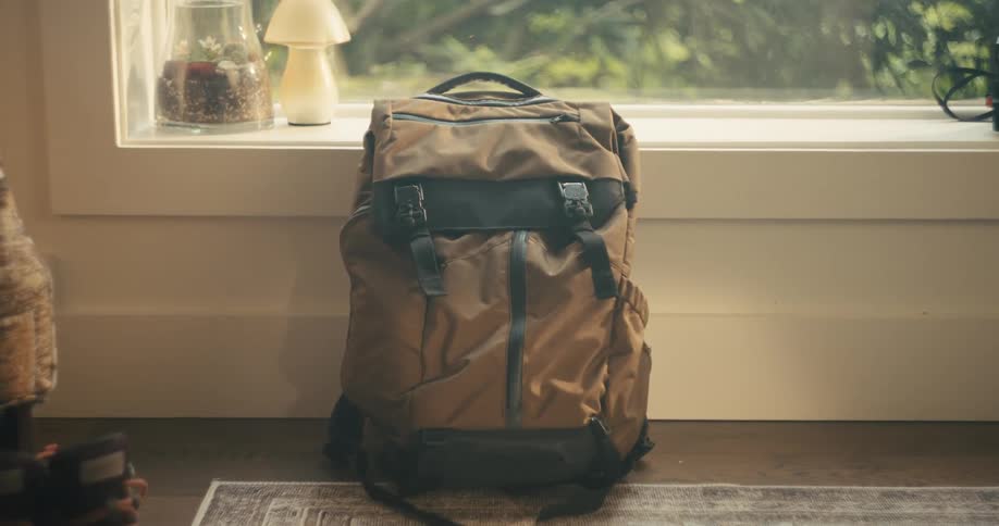 Backpack sits on floor next to large wndow