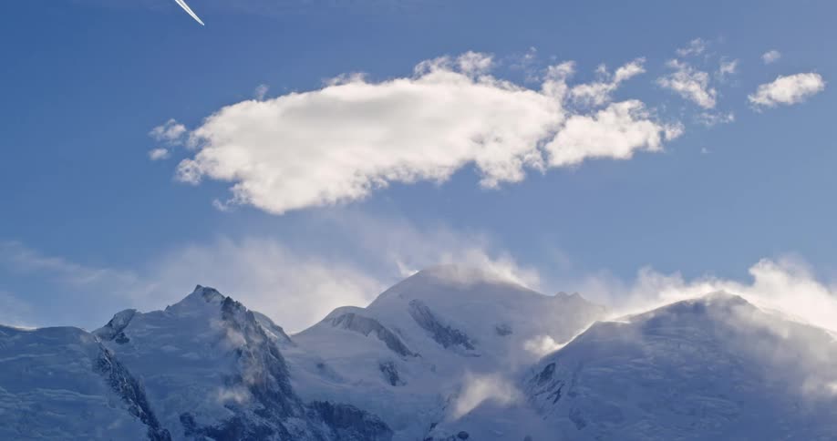 Clouds float over snow covered mountains