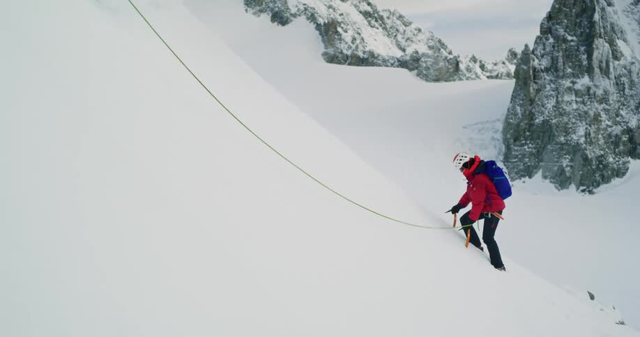 Panorama of a person climbing a snowcovered mountain with the help of a rope and stakes