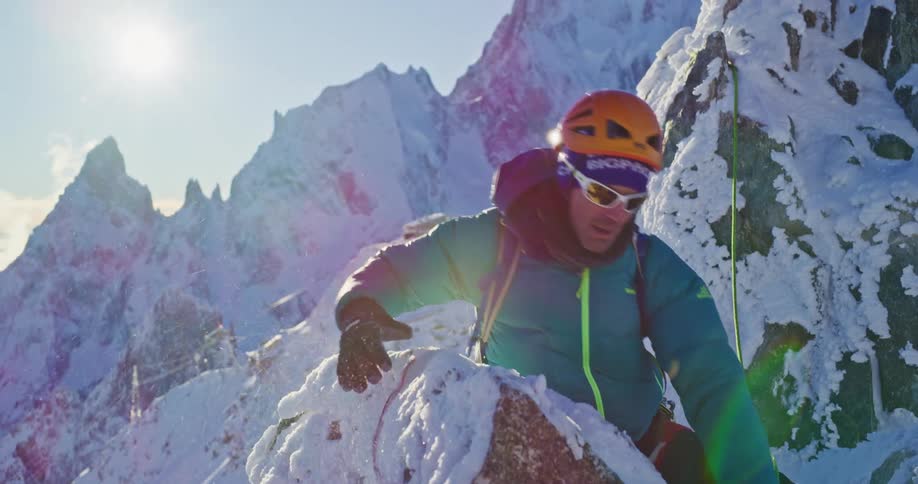 Mountaineer ties a rope around a rock in the snow covered mountains