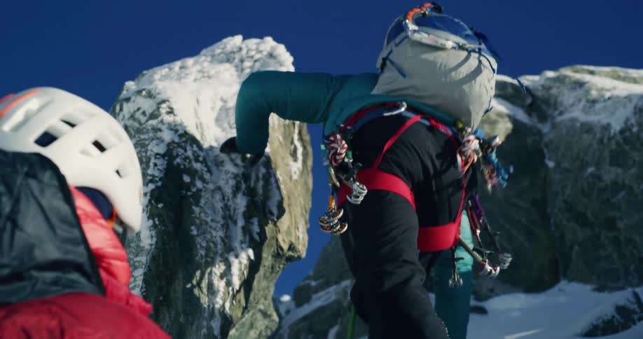 Mountain climbers moving up a rocky terrain in the snow during the day