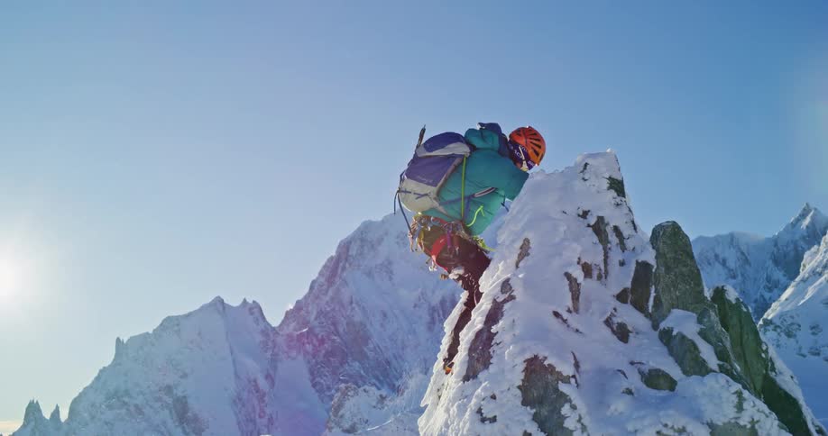 Mountaineer reaches the summit of a snow covered mountain