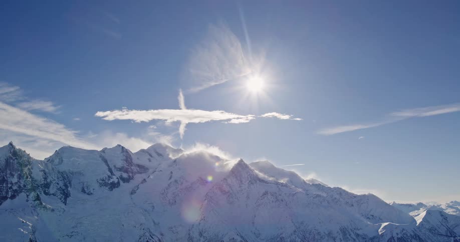 The sun shines over a snowcapped mountain range