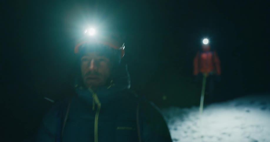 Mountaineers tied by security rope walk on the snow at night
