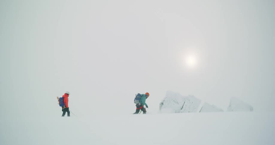 Two people walking in a completely snowy area