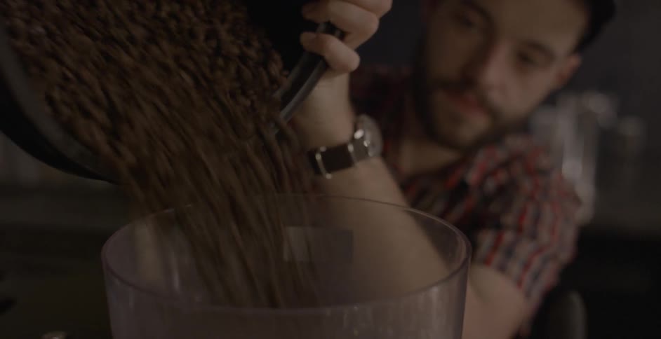 A man pours beans into a coffee grinder