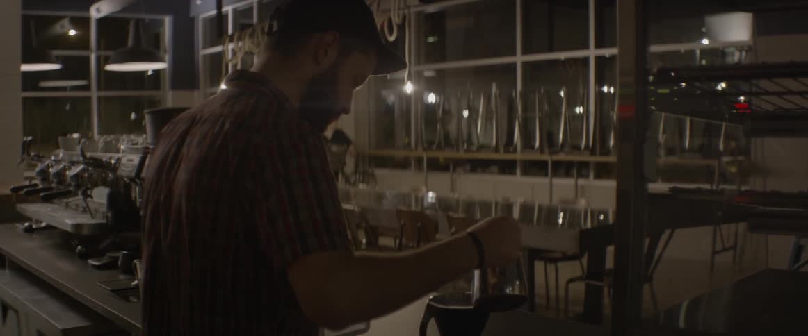A barista stirs in a canister behind the front counter