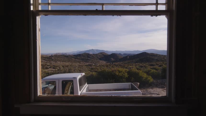 A large pickup truck is parked outside an open window