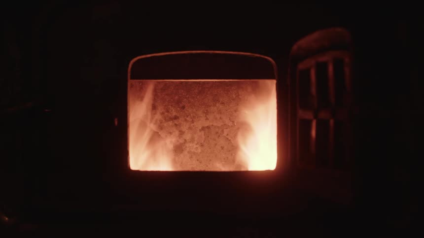 Flames rise up in an open iron oven