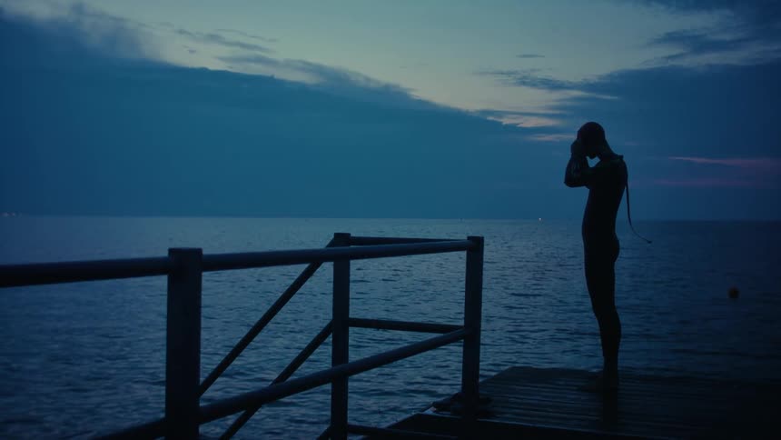 A man stands on the pier by the ocean
