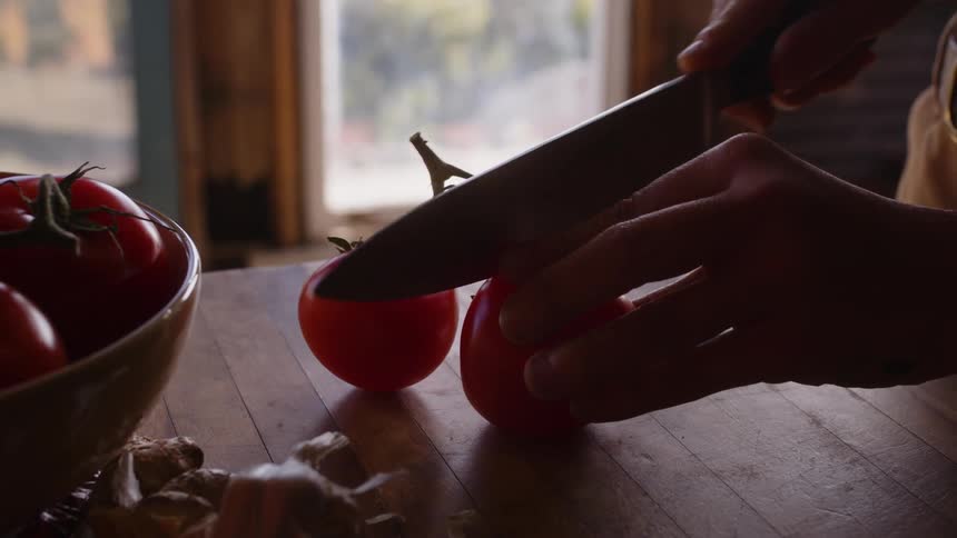 A person cutting fresh tomatoes in the kitchen at home
