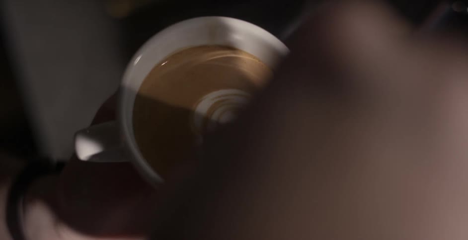 Person makes a latte adding foam in the shape of a heart