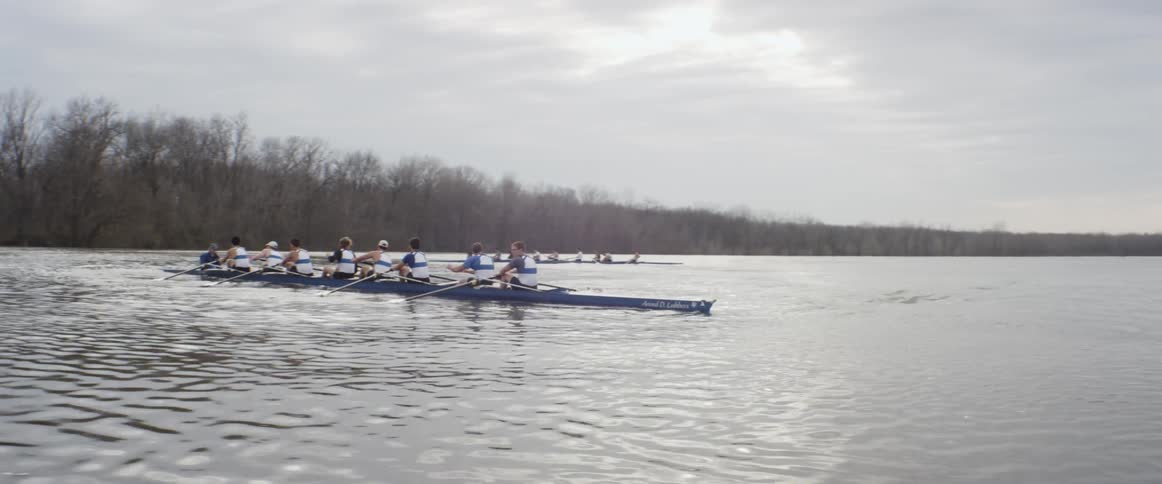 A rowboat team glides on a lake