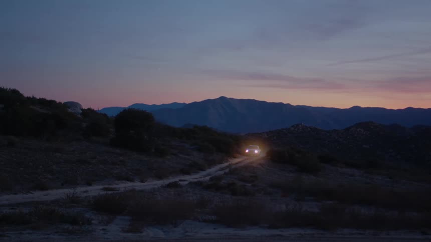 Pick up truck drives on a road through the countryside at evening