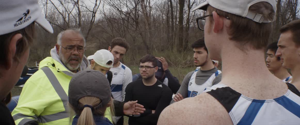 A group of people are listening to a man talking on a cloudy day