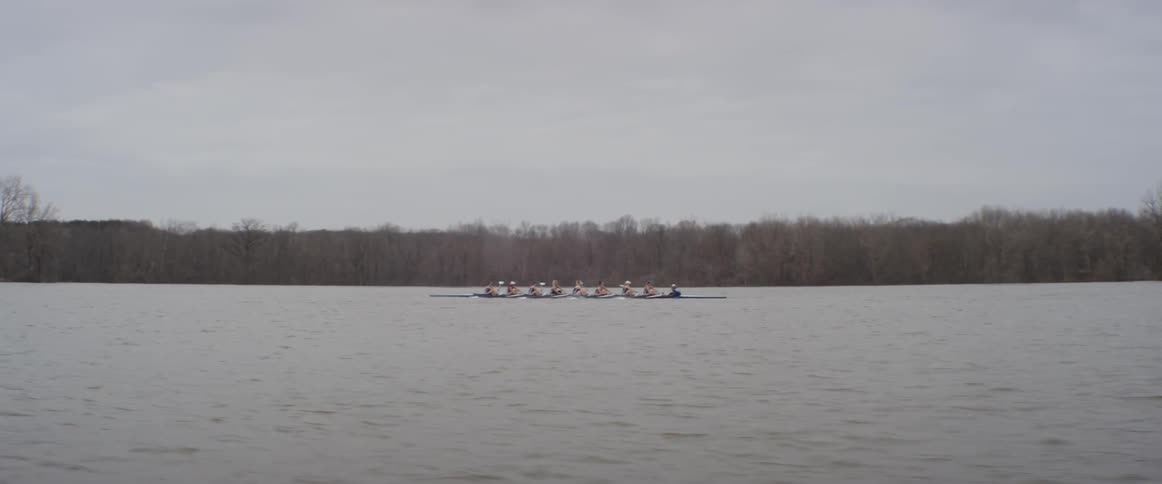 A rowboat teams floats on a lake on an overcast day