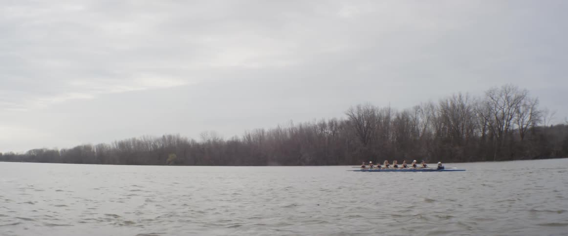 A group of people kayak on a river on a cloudy day