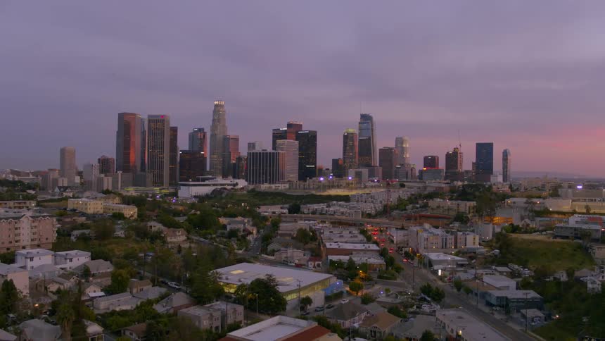 Tree tops and rooftops of a city skyline at sunset